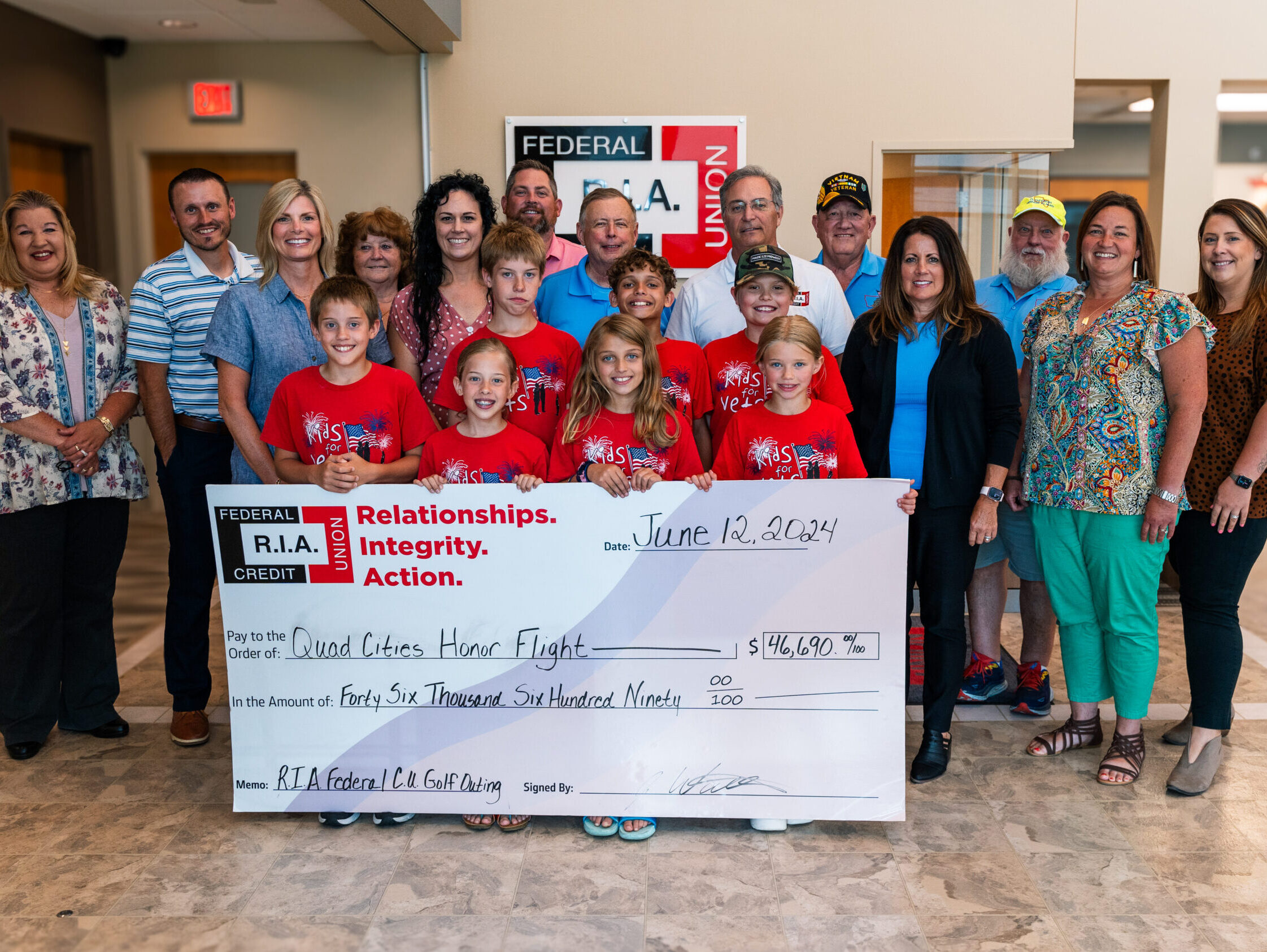 Group of employees and Kids for Vets kids holding a giant check to the Honor Flight