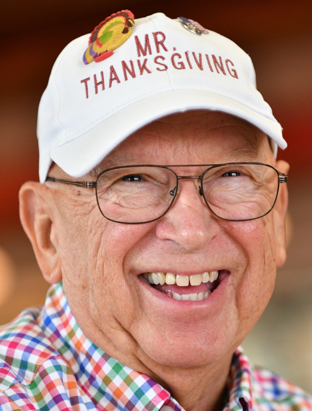 Mr. Thanksgiving smiling and wearing a white hat with red lettering that reads, "Mr. Thanksgiving"